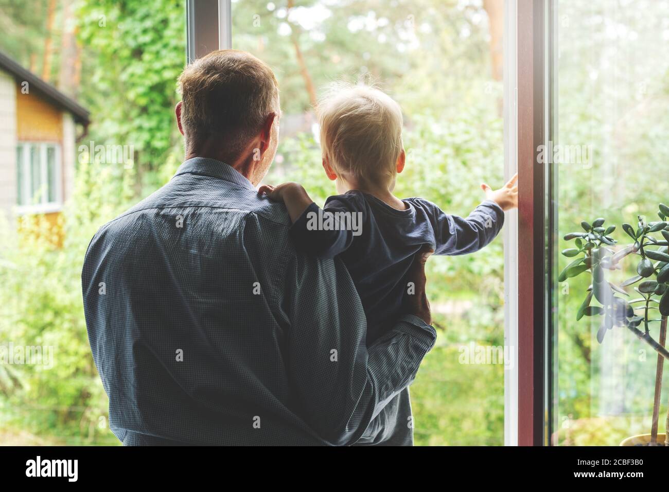 grandparenting - grandfather taking care and spending time together with grandson at home. looking through the window Stock Photo