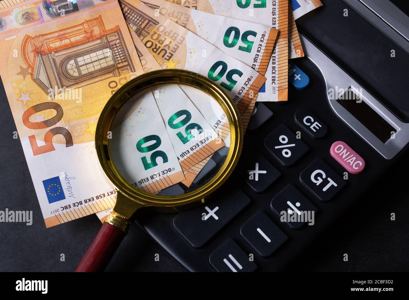 money with magnifying glass and calculator - concept of tax return, budget planning, accounting and market analysis Stock Photo