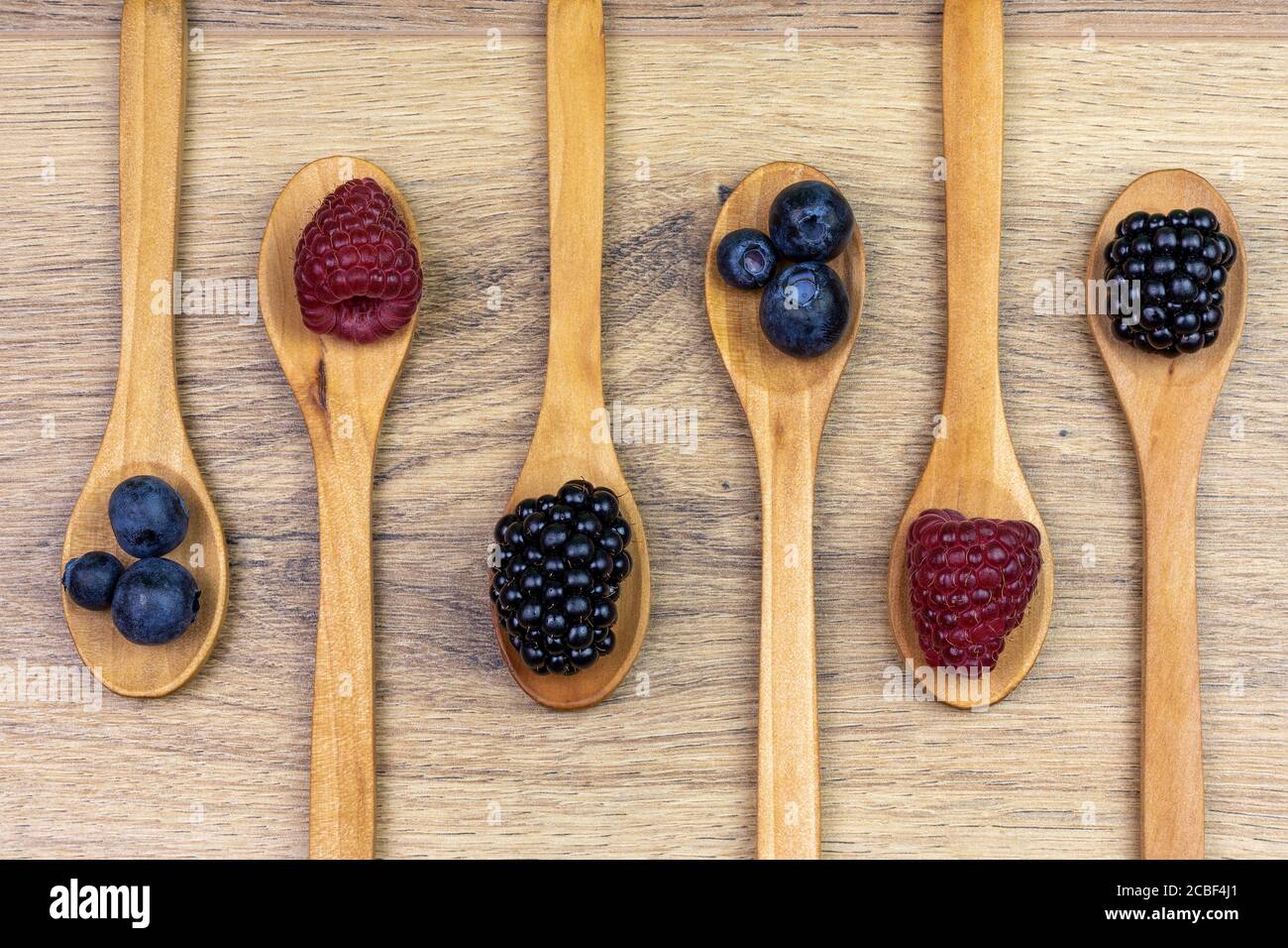 wooden spoons with blueberries, raspberries and blackberries Stock Photo