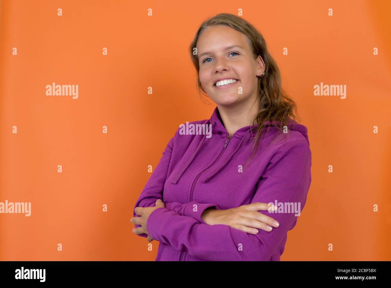 Beautiful blond german young adult woman with hoody isolated on orange background Stock Photo