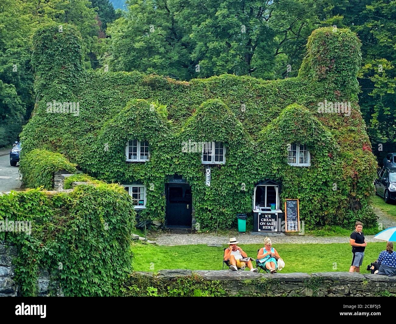 A couple read newspapers outside Tu Hwnt ir Bont Tea Rooms in Llanrwst