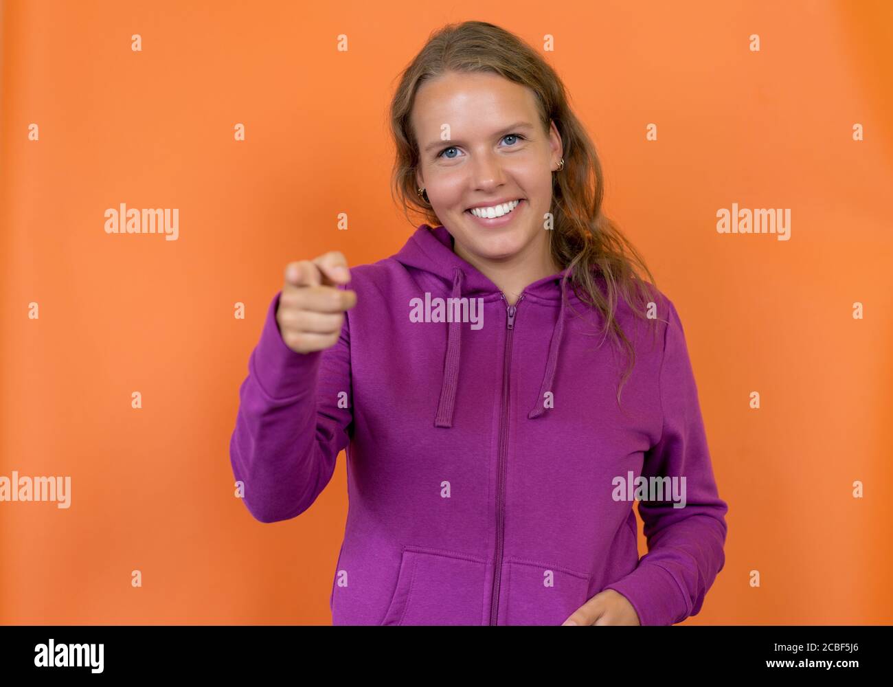 Laughing blond german young adult woman with hoody isolated on orange background Stock Photo