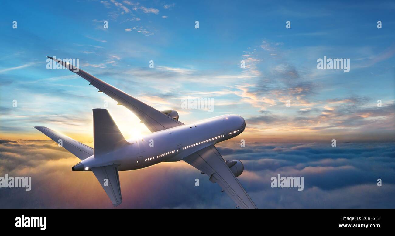 Passengers commercial airplane flying above clouds in sunset light ...