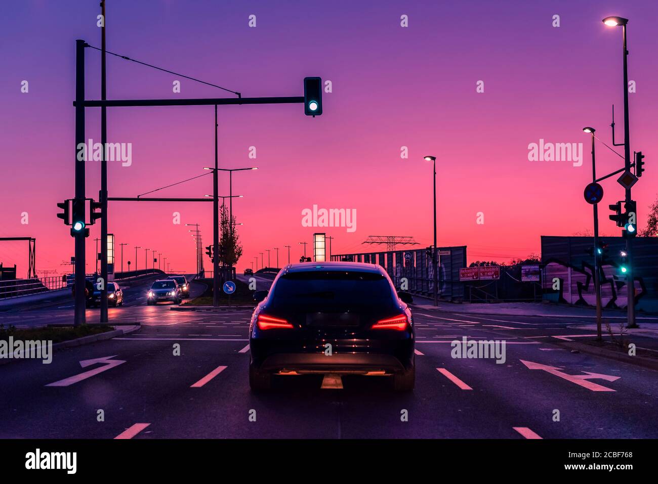 A car that is at a traffic light, in the sunset, car and colorful sunset, dusk Stock Photo