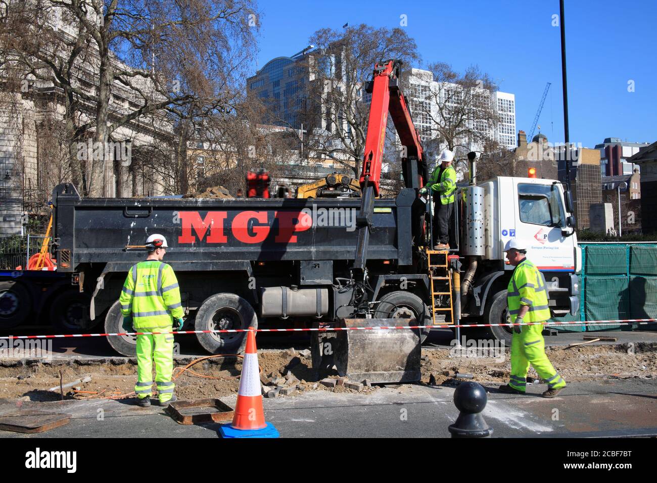 London, United Kingdom, Mar 19, 2011 : Roadworks in Tower Hill were manual workers are working as a team using a mechanical digger to make essential r Stock Photo