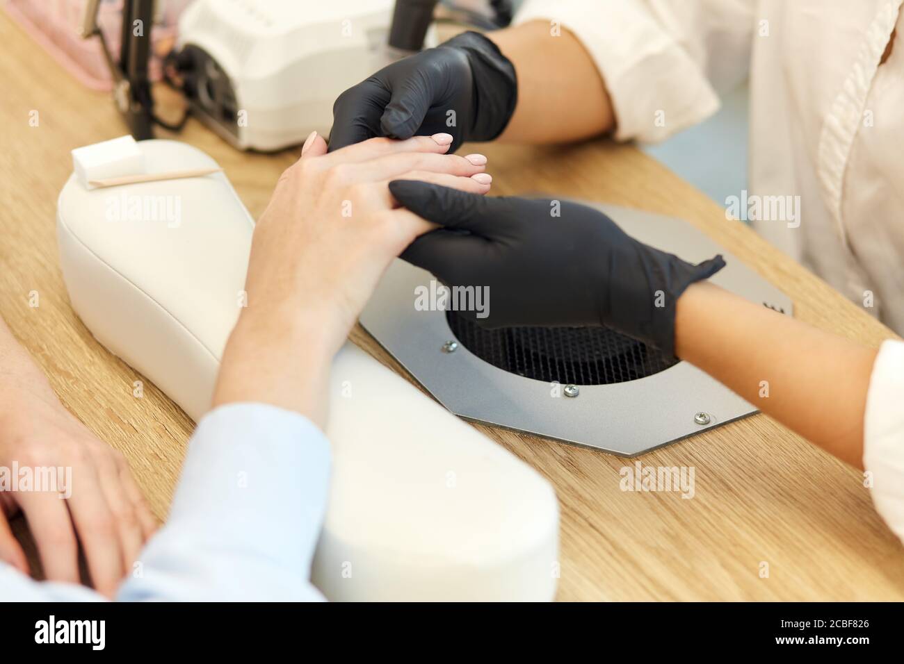 Master manicurist make nails procedure to beautiful young woman. Neatness and cleanliness in salon. Close-up photo Stock Photo