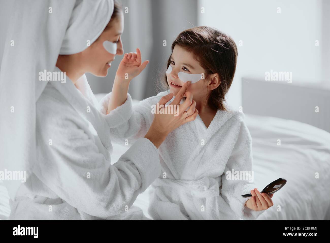 beauty concept. careful attentive mother use patches for eyes and her daughter in mask too. parents and children interested in beauty procedures Stock Photo