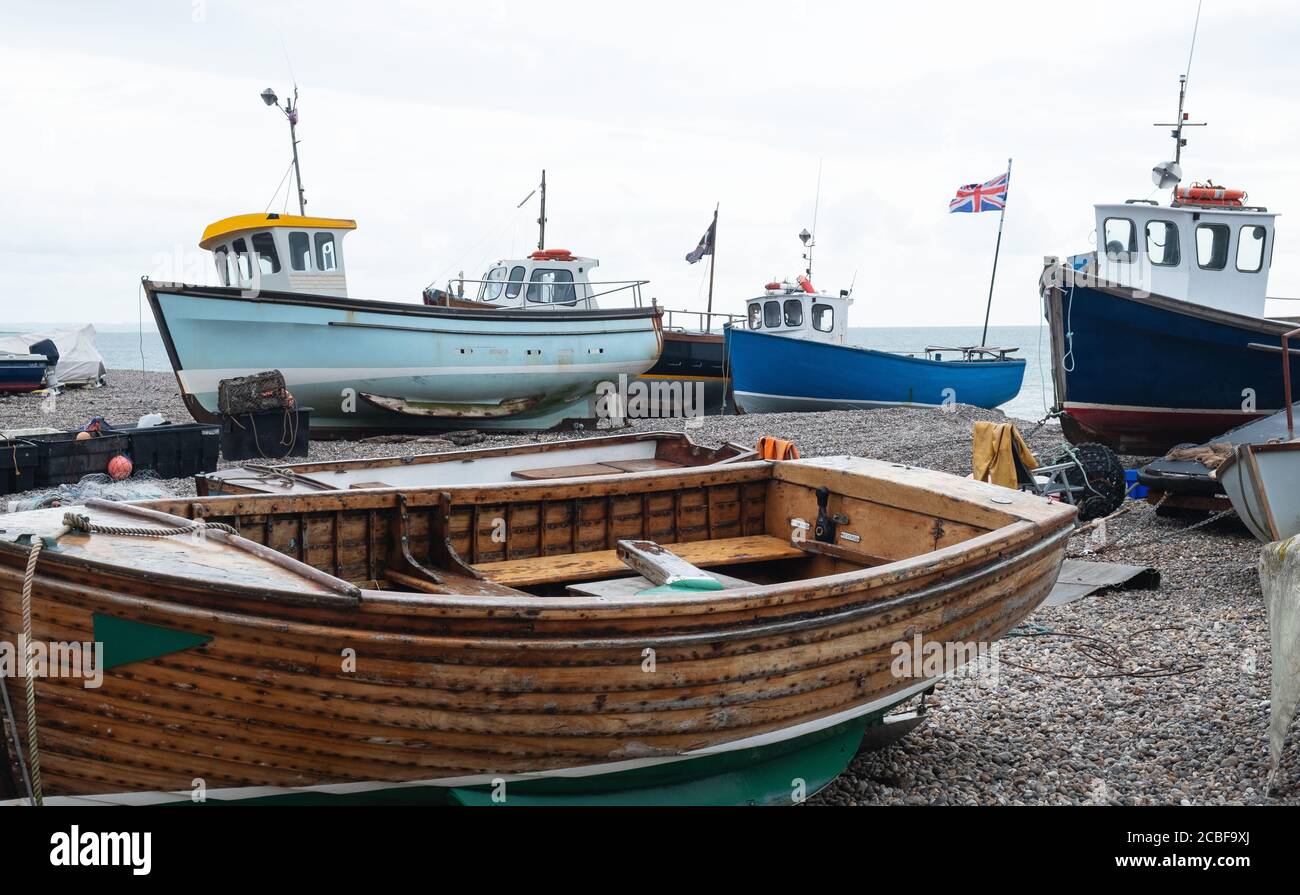Some of the local fishing fleet stranded on the pebble beach at Beer in south east Devon, UK. Vessels are towed to and from the sea by tractor Stock Photo