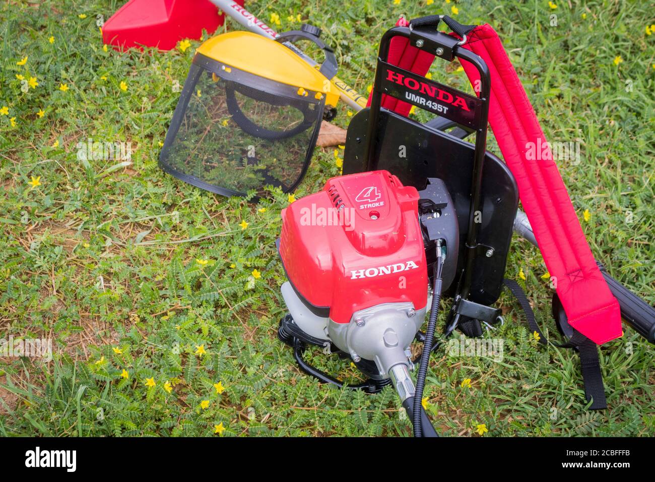 A red Honda grass trimmer which is UMR 435t model and a yellow safety