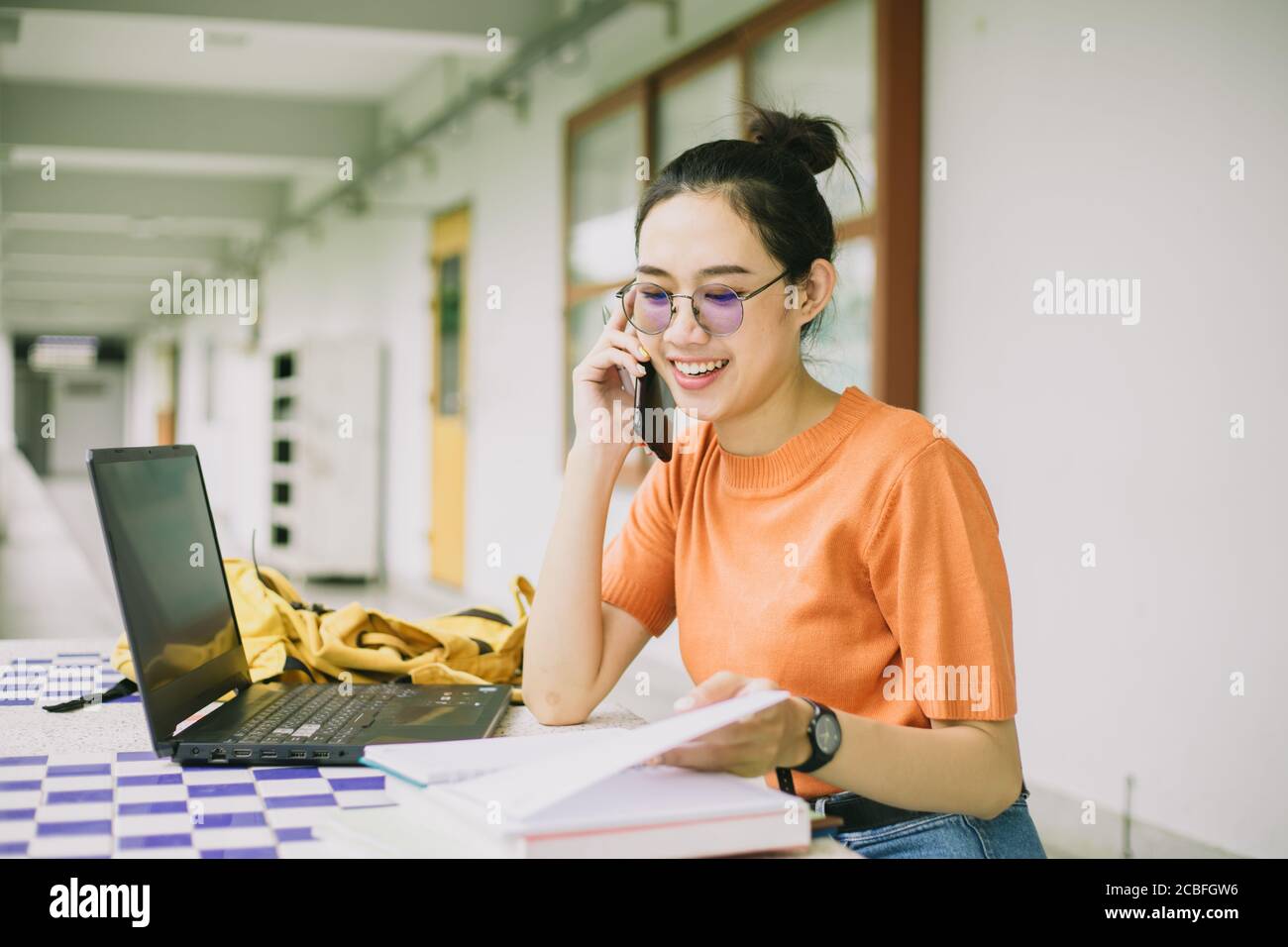 University girl teen using phone call talking with friend while working in campus Stock Photo