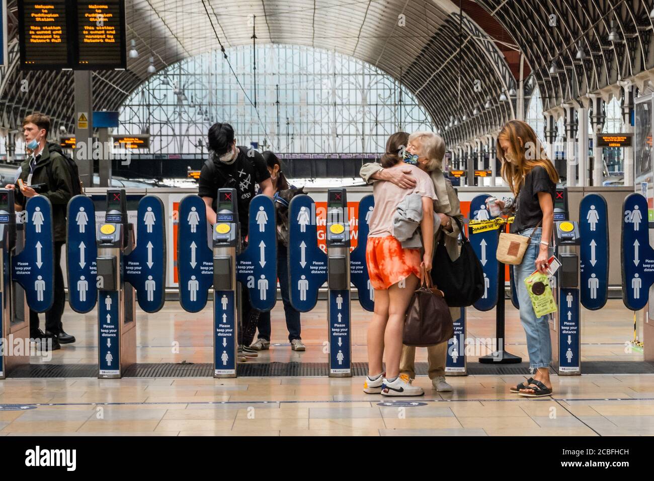 London, UK. 13th Aug, 2020. An old lady greets children with a hug - Paddington station remains relatively quiet - there are signs warning people to wear masks and not to maintain social distancing. The 'lockdown' continues for the Coronavirus (Covid 19) outbreak in London. Credit: Guy Bell/Alamy Live News Stock Photo