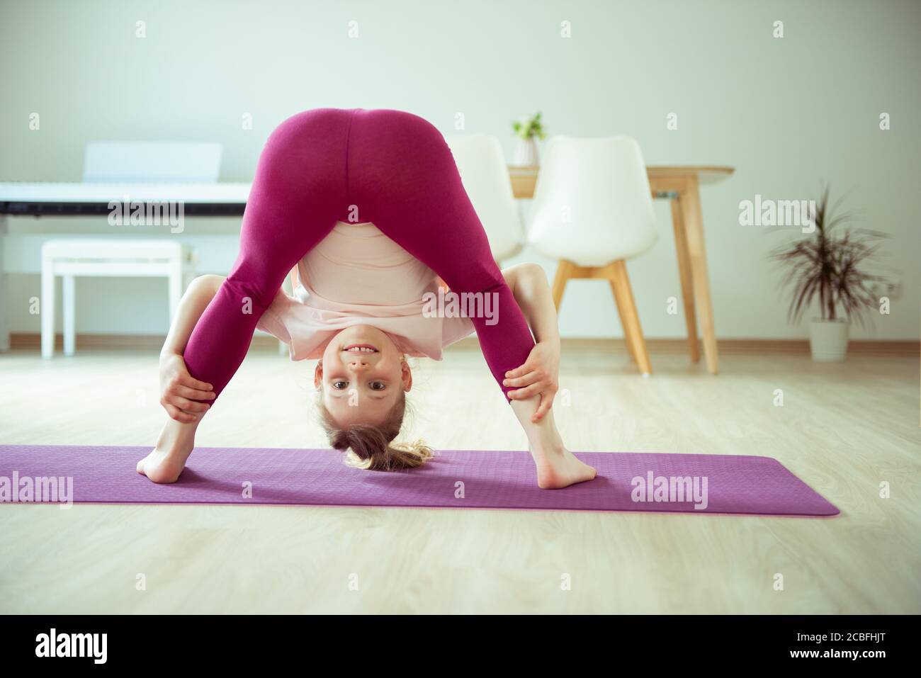 Pretty happy child girl having fun making yoga exercises at home Stock ...