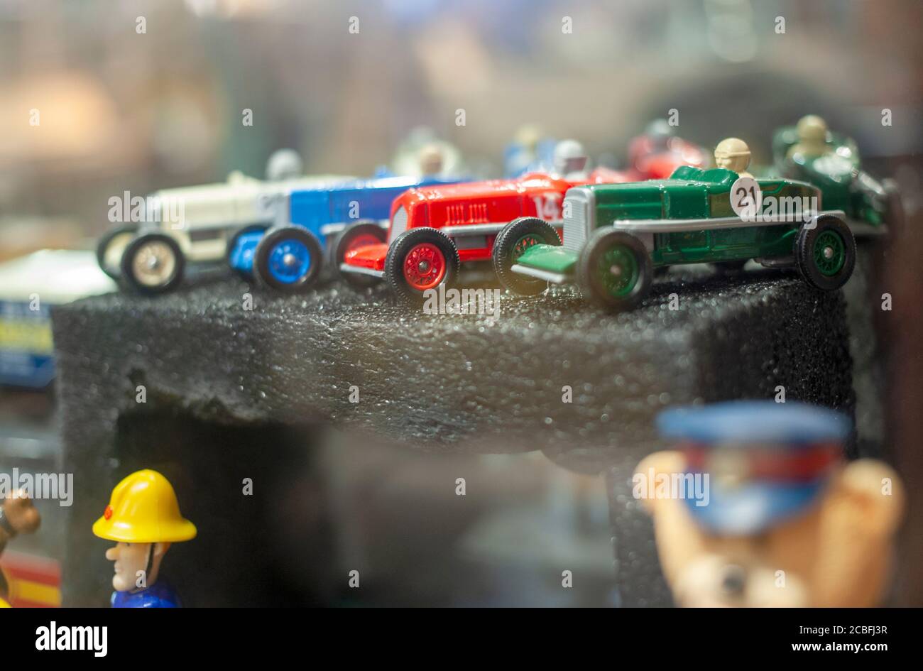 Collection of miniature vintage matchbox die-cast racing cars displayed in a glass cabinet. Stock Photo