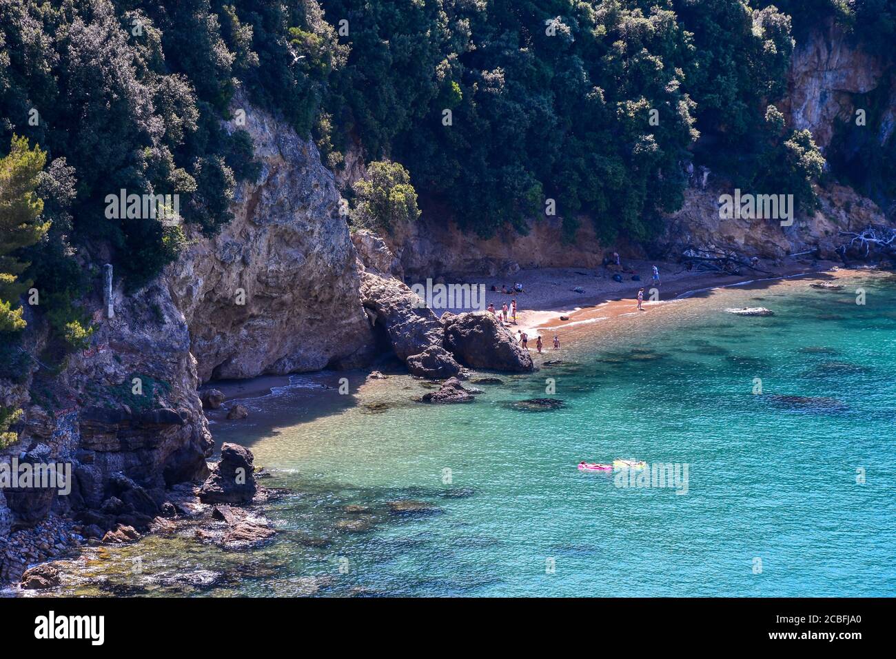 High-angle view of a bay with vacationers on a little beach at the foot of a cliff on the sea shore of the Gulf of Poets, Lerici, La Spezia, Italy Stock Photo