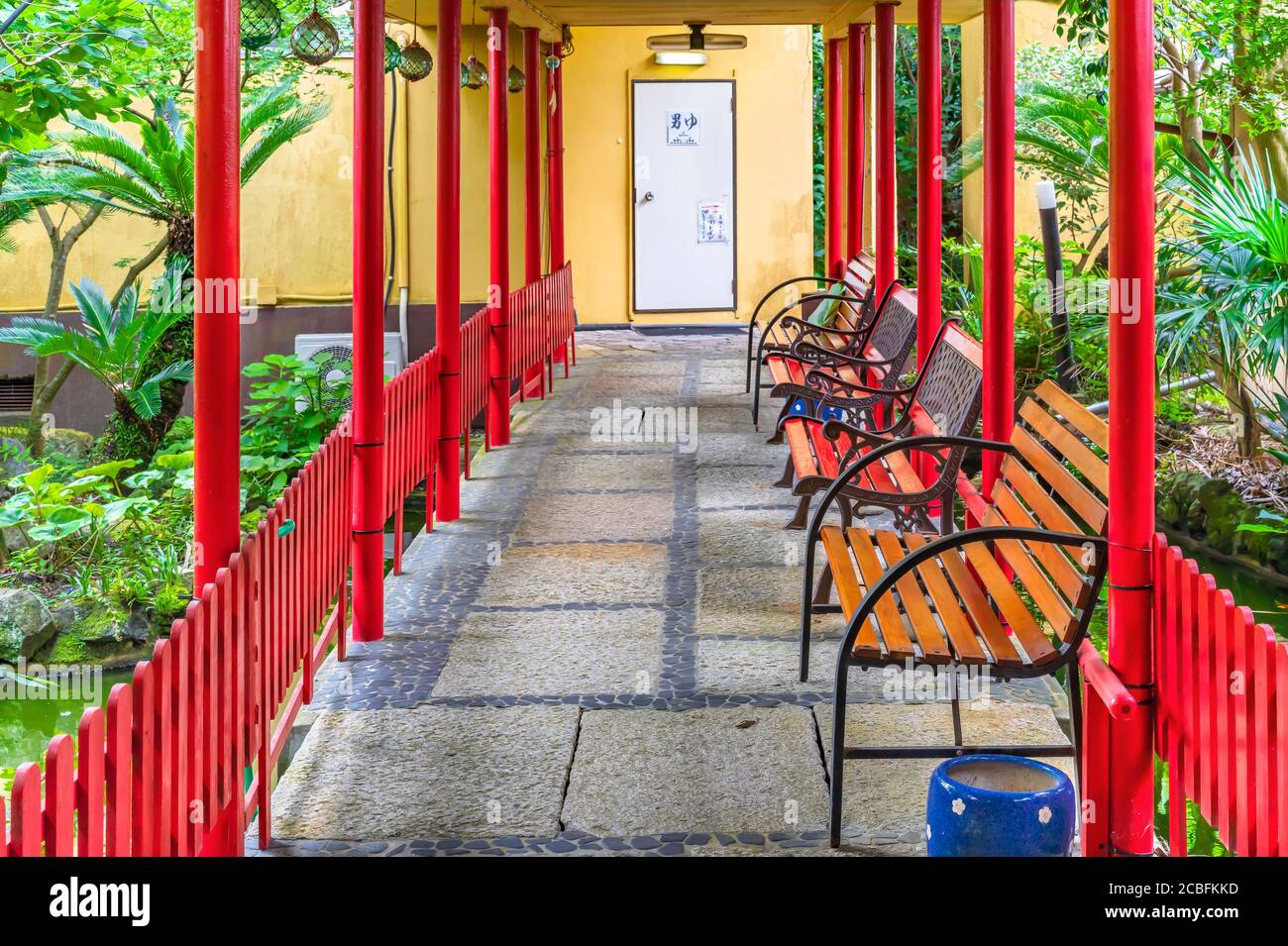chiba, japan - july 18 2020: Hallway leading through the garden pond of a ryokan guesthouse to onsen hot spring surrounded by benches, pillars and jap Stock Photo