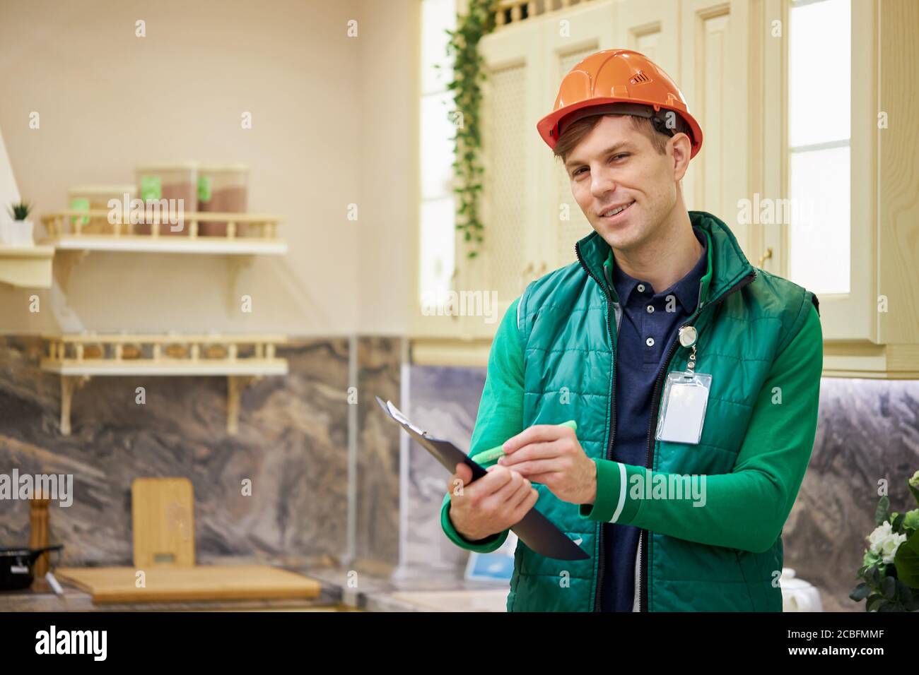confident caucasian man warehouse worker check quantity of commodity in market, look on document and make notes if something is missing, smile and loo Stock Photo