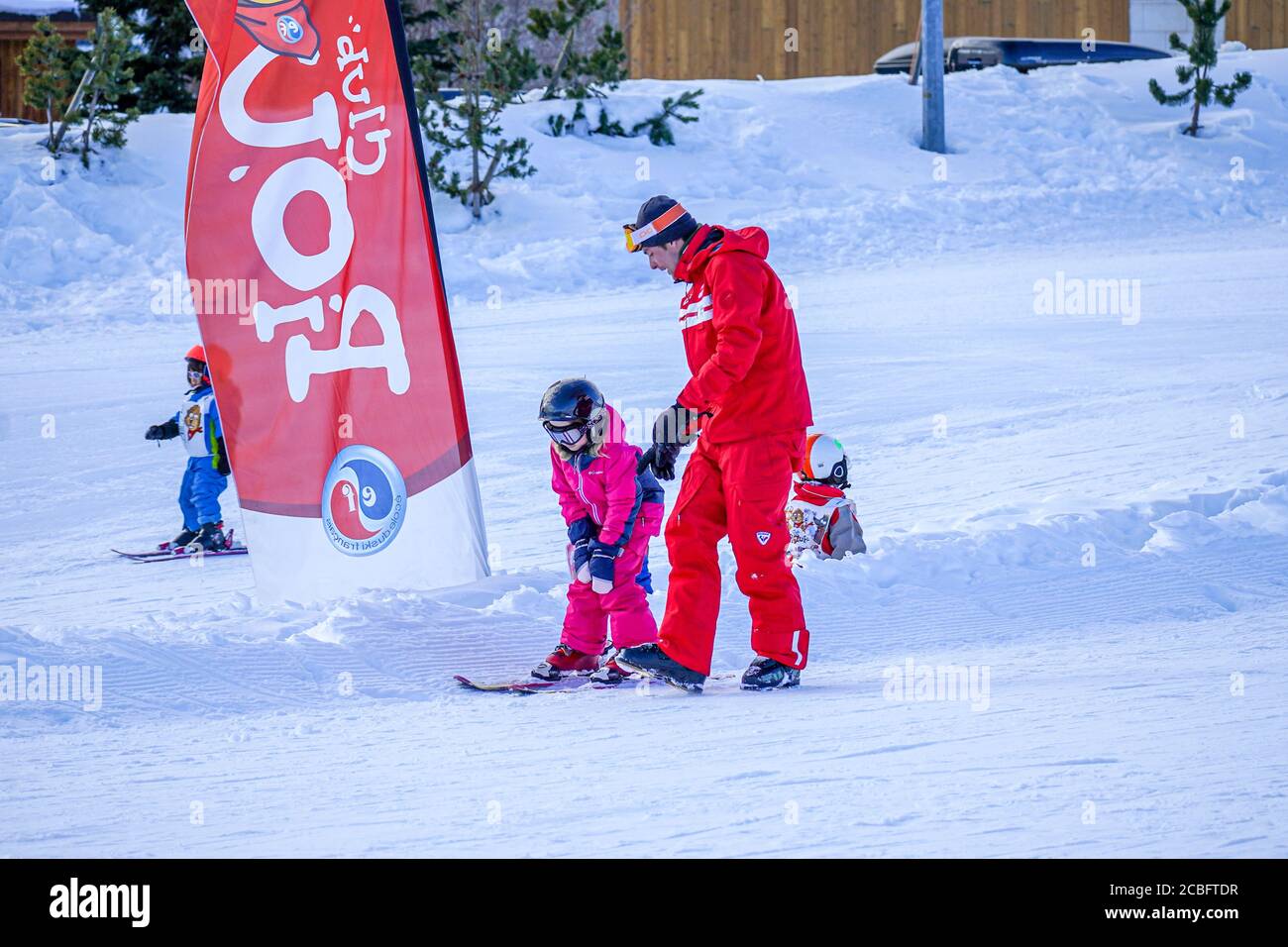 L'Alpe D'Huez, France 02.01.2019 Professional ski instructor is teaching a child to ski on a sunny day on a mountain slope resort. Family and children active vacation. Stock Photo