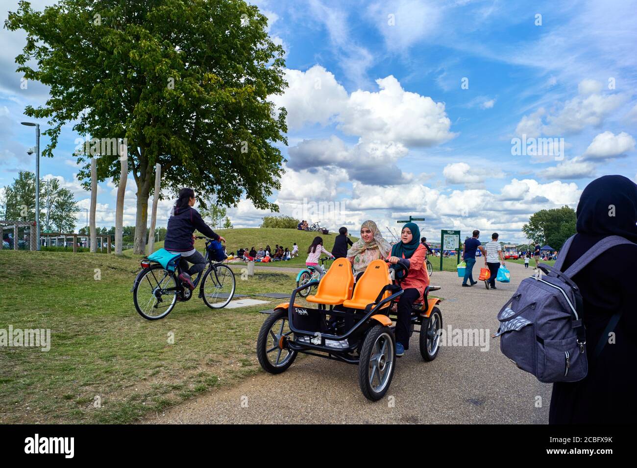 Two asians girls wearing head coverings on a four wheeled bike at Willen Lake, Milton Keynes Stock Photo