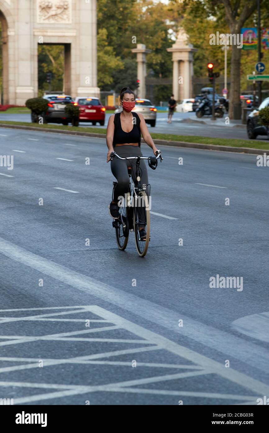 Madrid, Spain - August 8, 2020: A rider her bike to work and wears a mask to protect herself from the Covid-19 Stock Photo