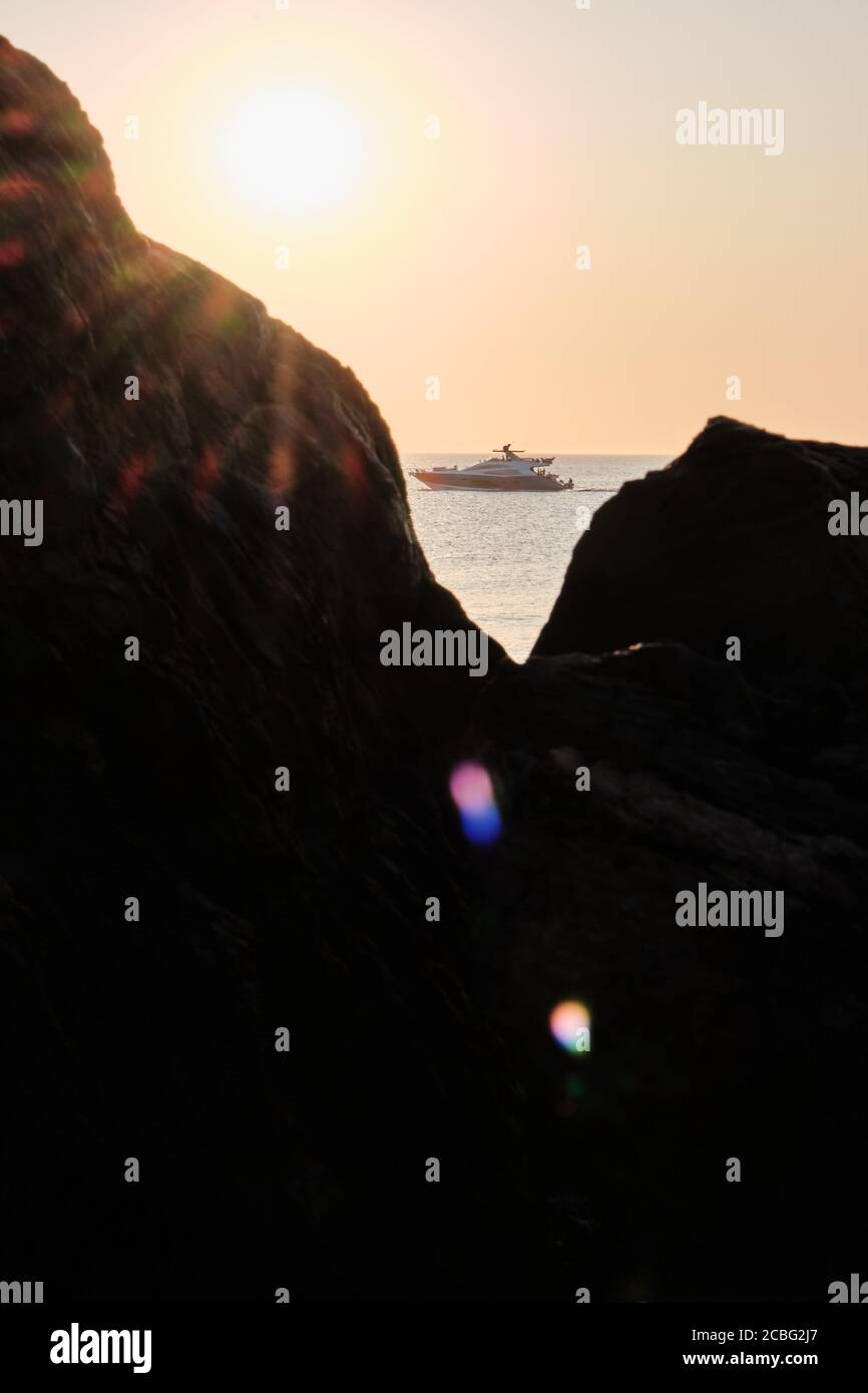View of the sun burst or the star sun over the rock with the sunset at the background in the atlantic ocean, Punta Ballena, Maldonado, Uruguay Stock Photo