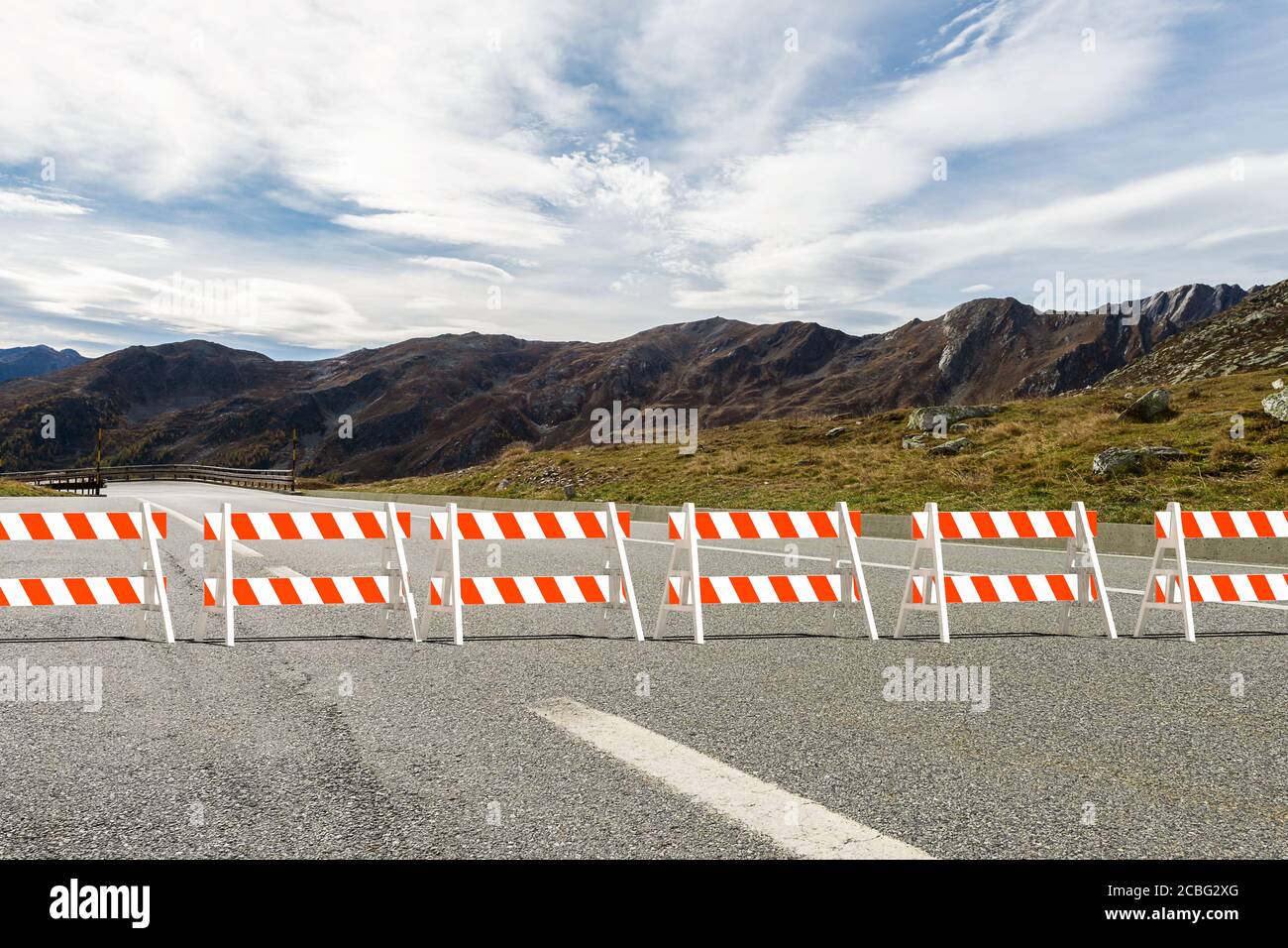 Red and white plastic a-frame barricades set across the road block the passage - in the background a view of the mountains - 3d illustration Stock Photo