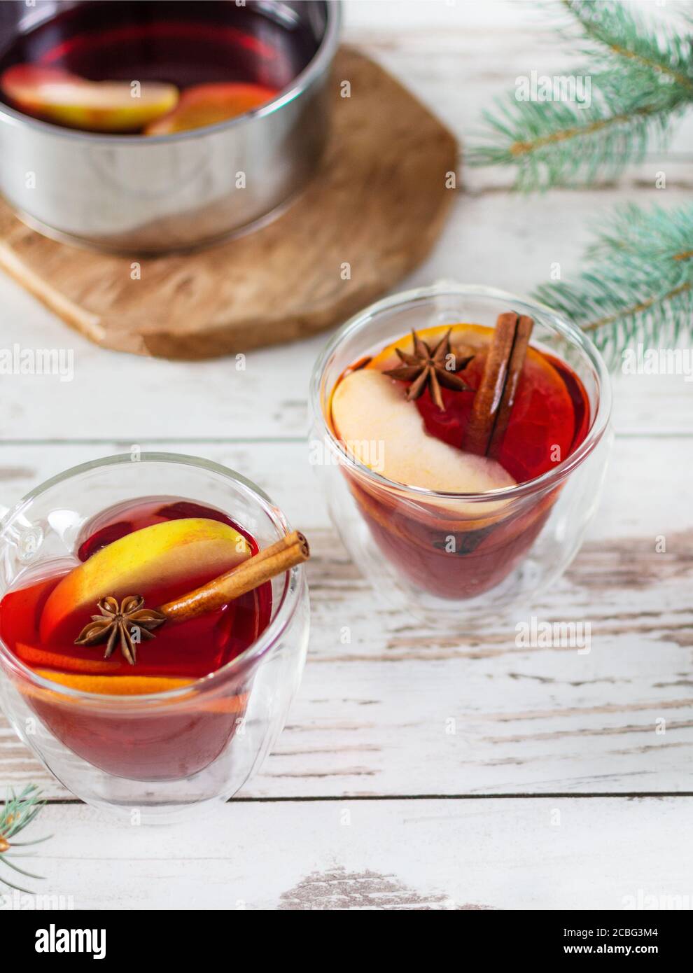 Christmas mulled red wine with spices and fruits over Christmas decorated background. Traditional hot drink made from red wine at Christmas time. Stock Photo