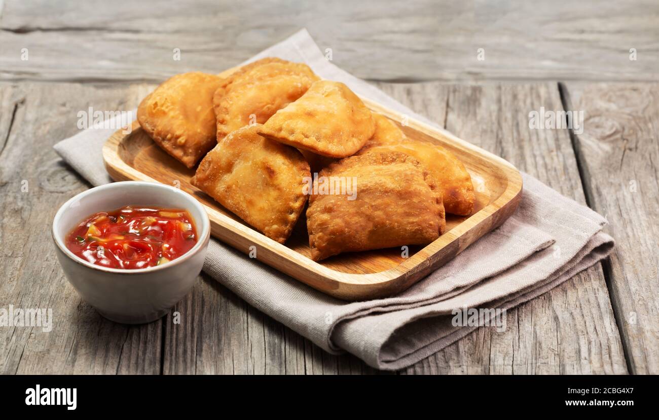 Typical Colombian empanadas served with spicy sauce on wooden surface Stock Photo