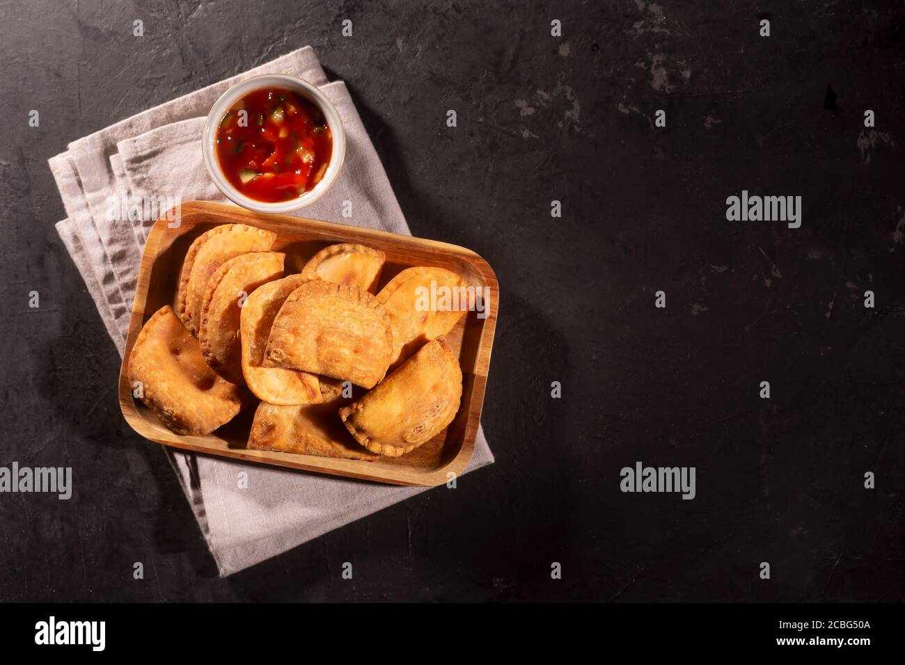 Typical Colombian empanadas served with spicy sauce on black background Stock Photo