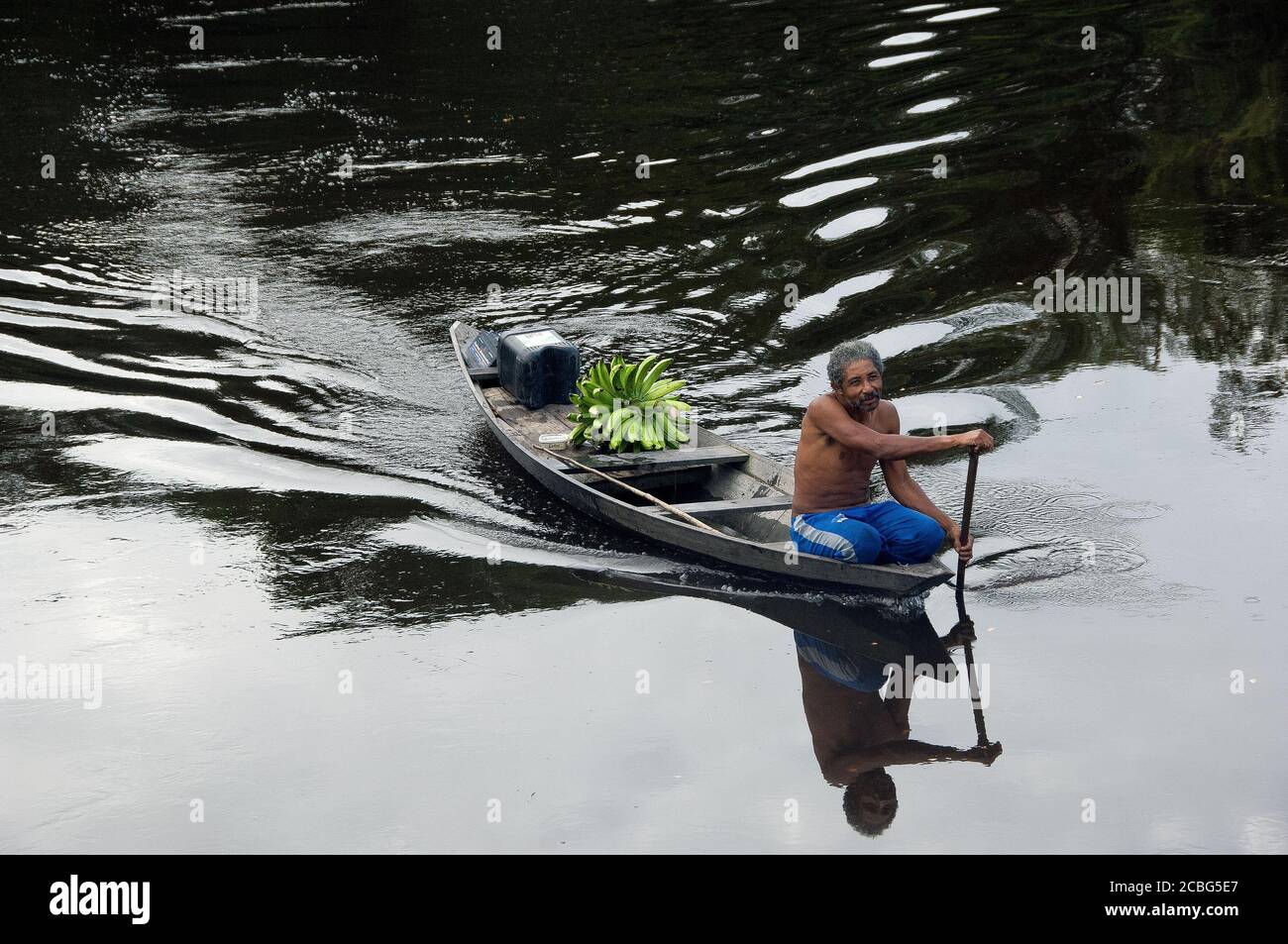 indigenous in canoe transports bananas on the Amazon river Stock Photo