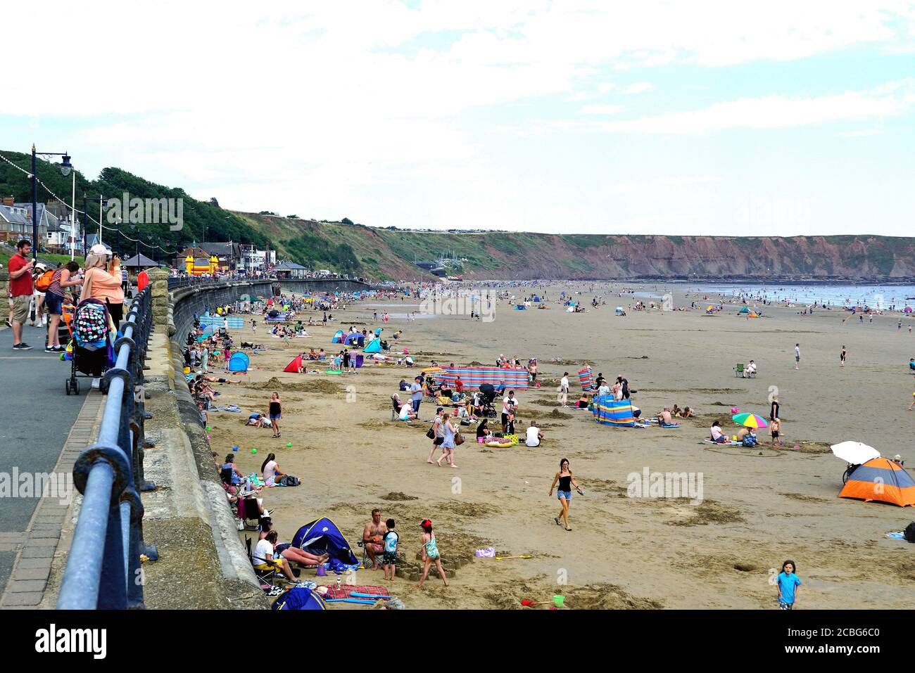 Filey, Yorkshire, UK. August 07, 2020. Holidaymakers relaxing on the beach and promenade after lockdown at Filey in Yorkshire, UK. Stock Photo
