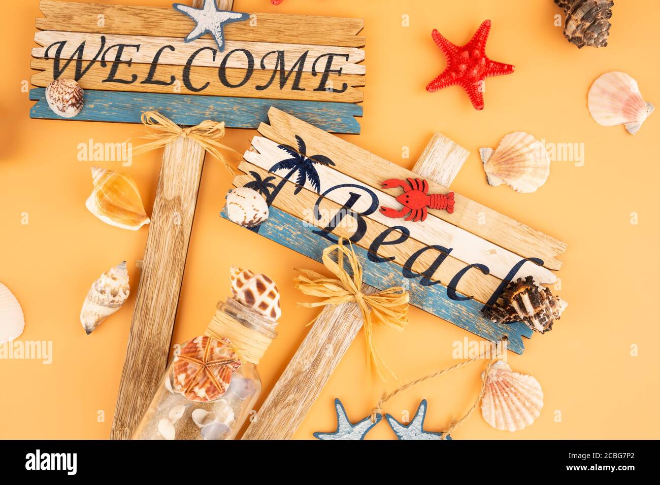 Wooden signs welcome beach, starfish and shells on yellow background