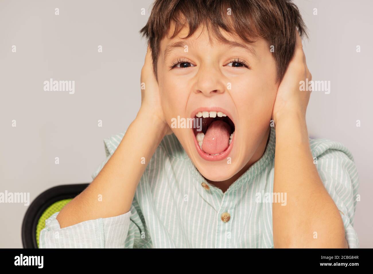 Sad screaming autistic boy portrait close ears with hands, sensory integration problem Stock Photo
