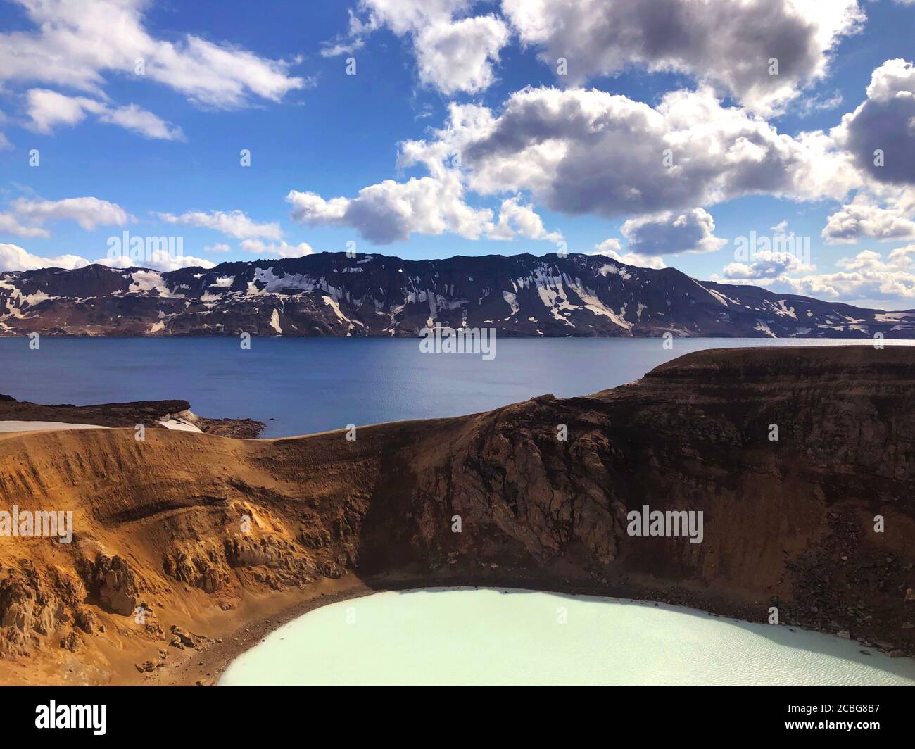 View of Viti Crater of Krafla Caldera with Geothermal Lake and Mountains in the Distance Stock Photo