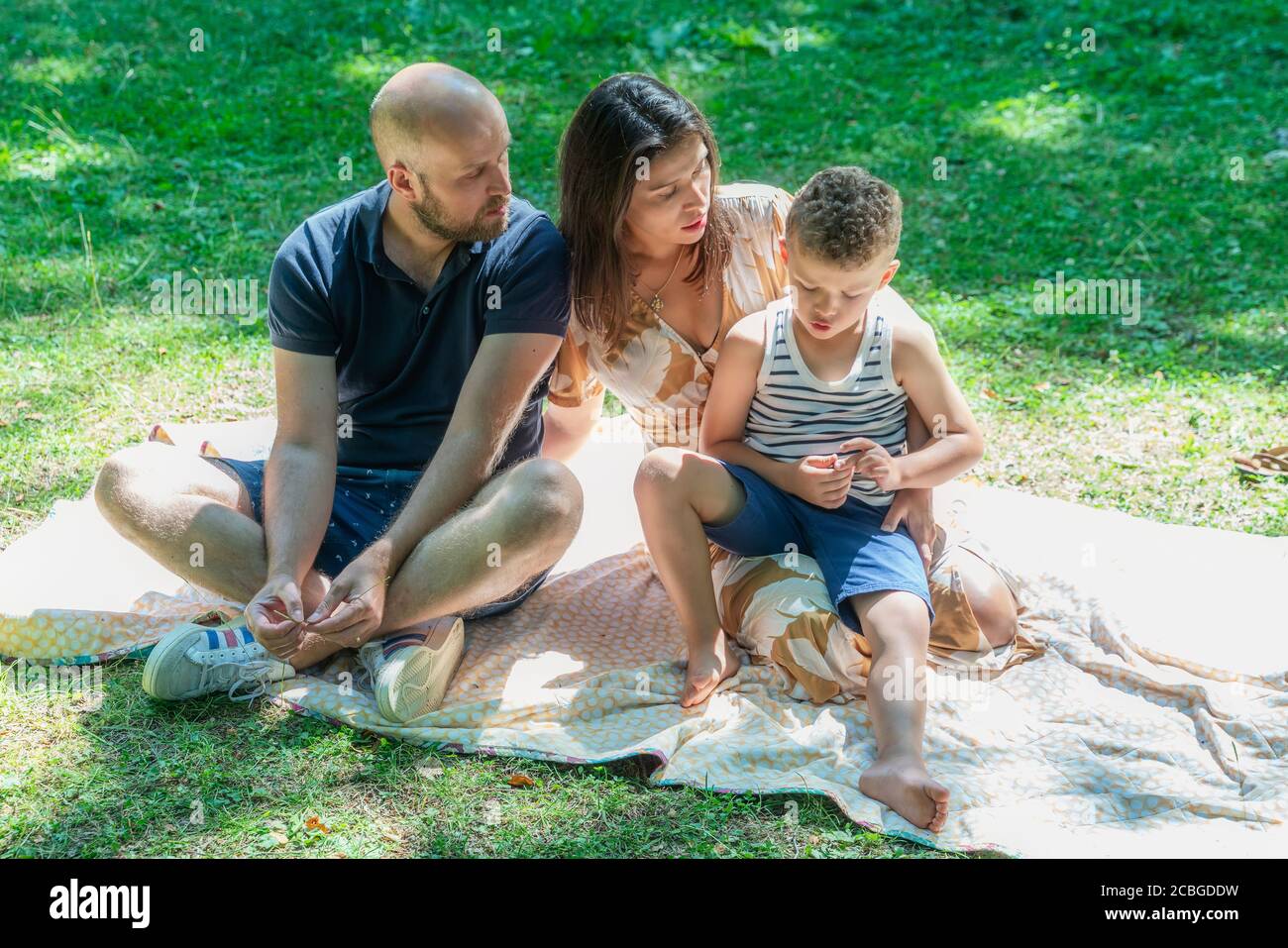 French family sitting on the lawn together on a new normal vacation Stock Photo