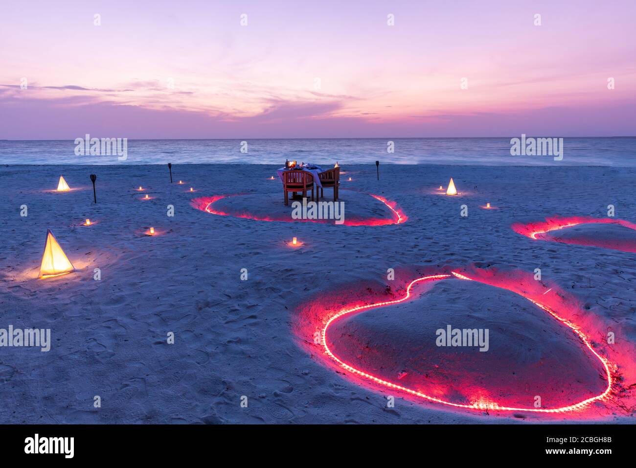 A young couple share a romantic dinner with candles heart on the sea ...