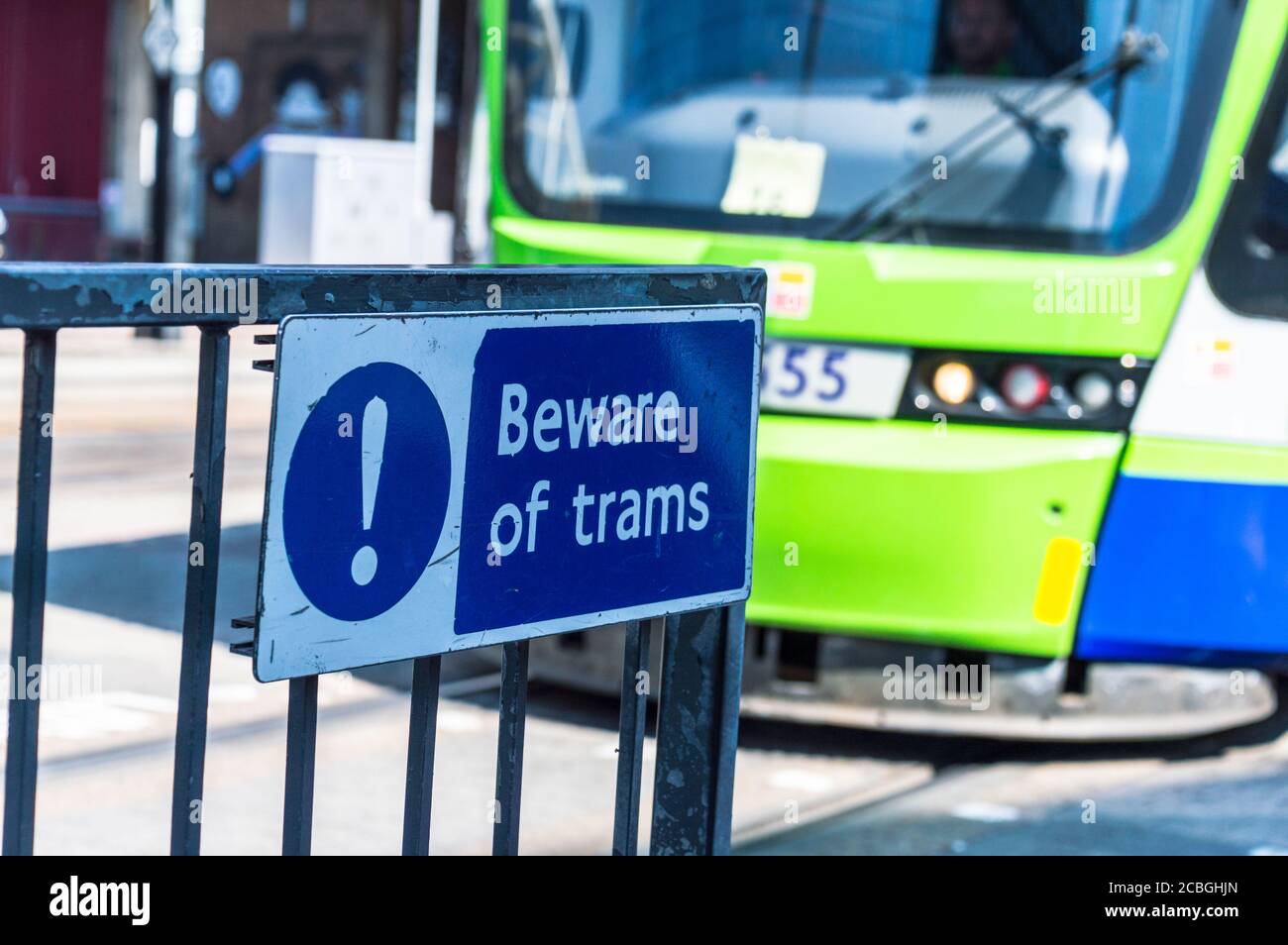 Beware of Trams  warning at crossing point with Tram in background Stock Photo