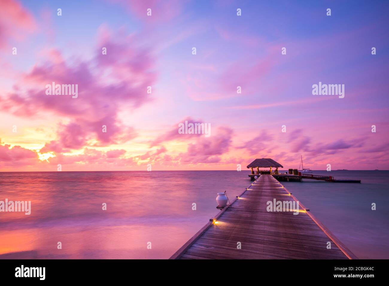 Maldives island sunset. Water bungalows resort at islands beach. Indian Ocean, Maldives. Beautiful sunset landscape, luxury resort and colorful sky. Stock Photo