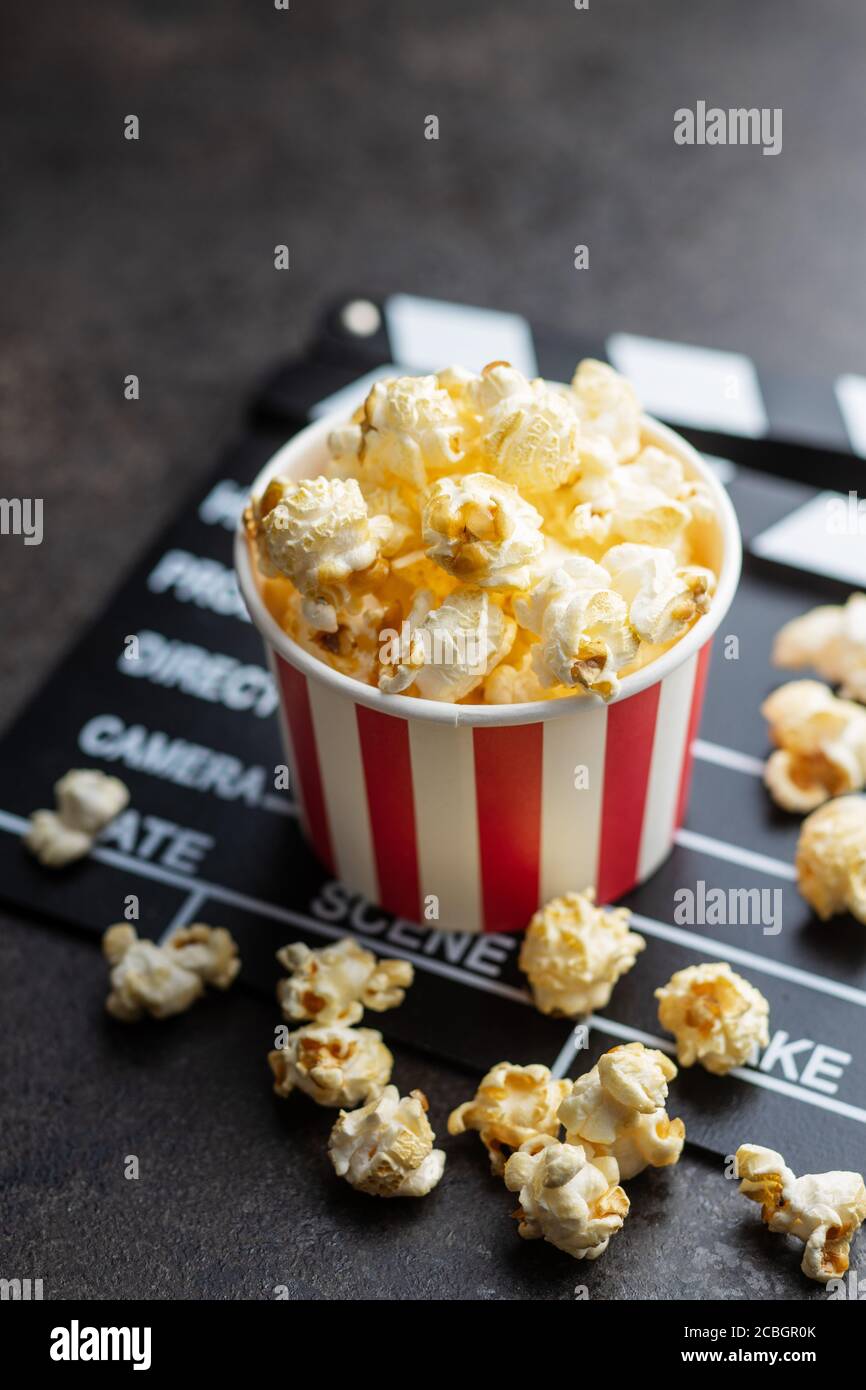 Sweet popcorn in cup and clappeboard on black table. Stock Photo