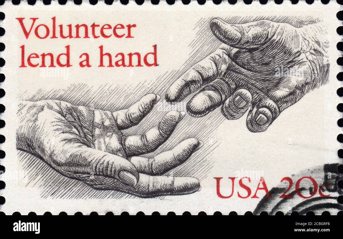 London, UK, February 5 2011 - Vintage 1983 USA cancelled postage stamp  showing an image of two engraved hands saying volunteer lend a hand Stock Photo
