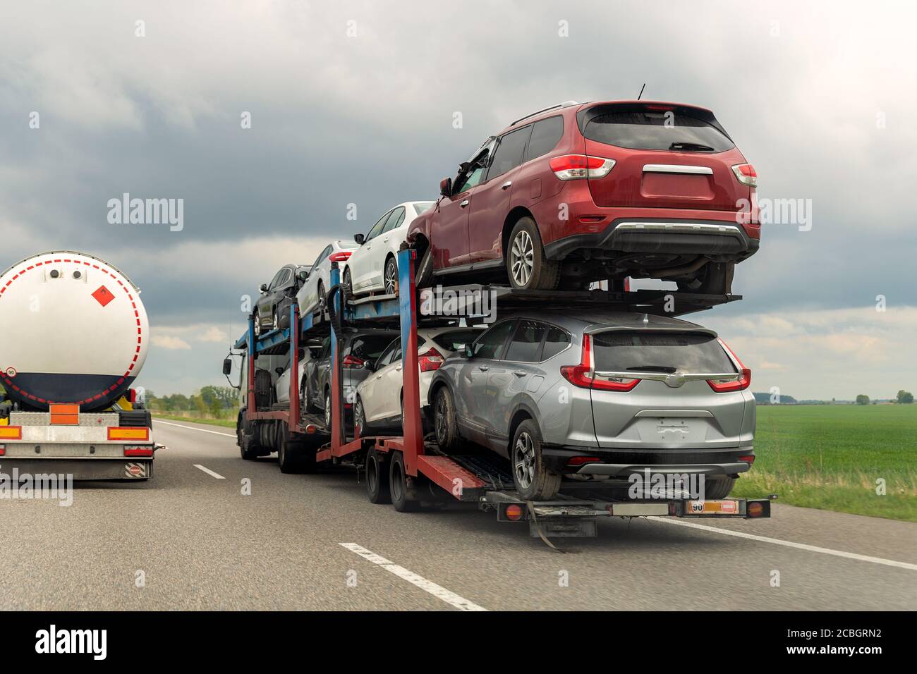 Tow truck car carrier semi trailer on highway carrying batch of damaged cars sold on insurance