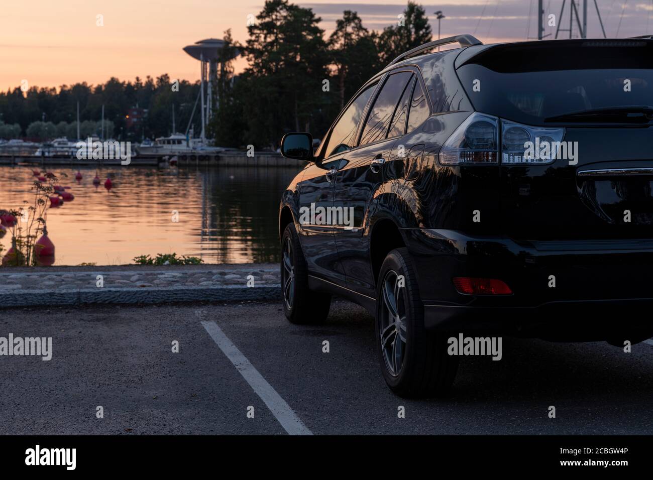 Black shiny SUV facing colourful Finnish sunset in Espoo Stock Photo