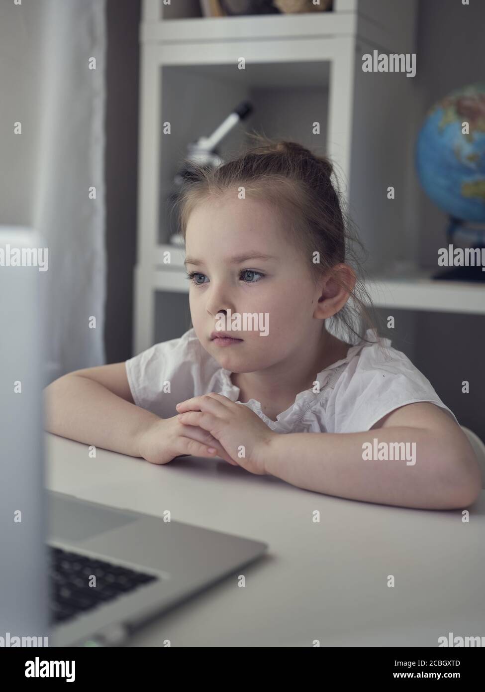Cute little girl using laptop at home. Education, online study, home studying The girl at home communicates with friends on the Internet. Kids distance learning. . High quality photo Stock Photo