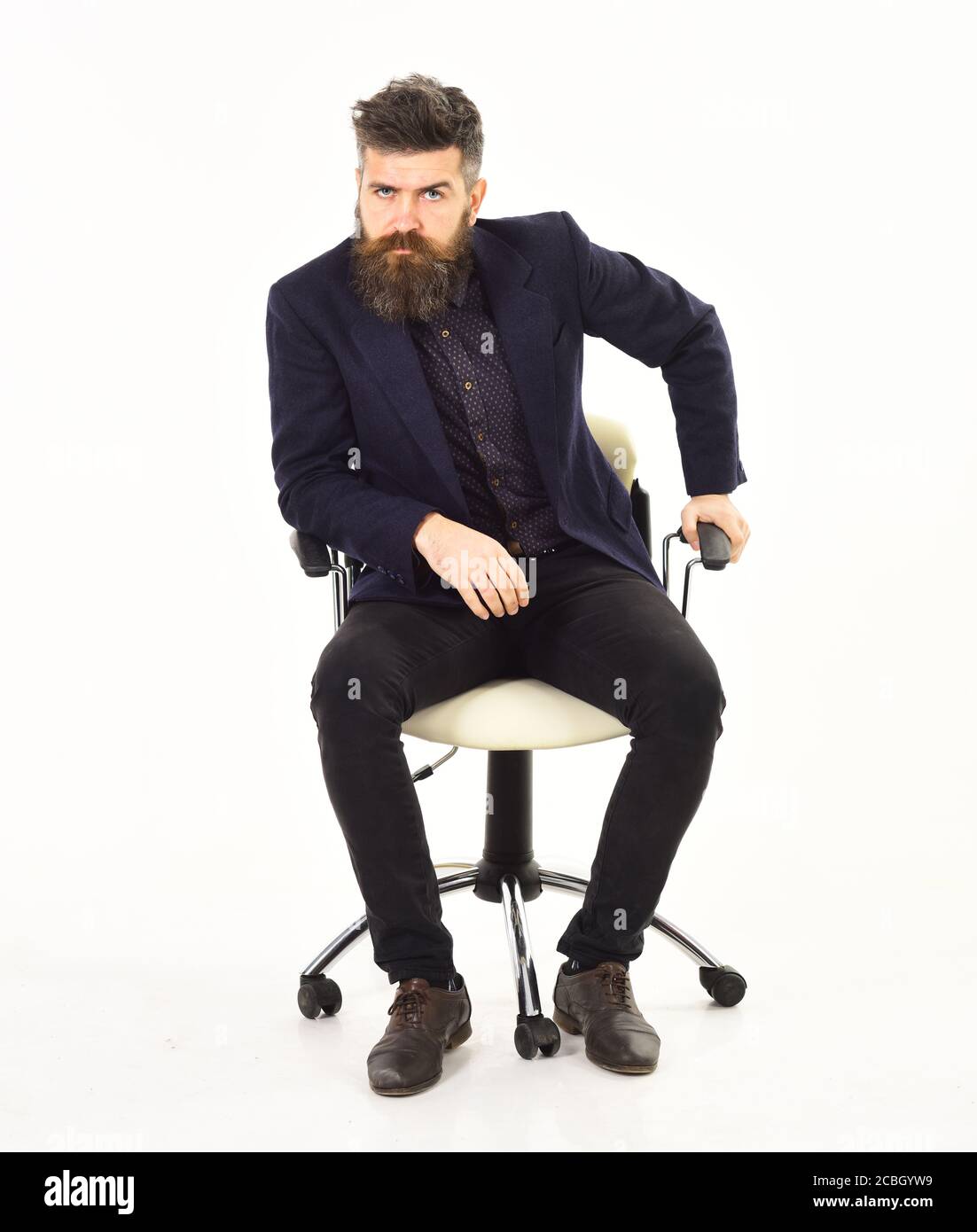 Business, success, leadership concept. Boss with serious unsatisfied face. Employer sits in luxury chair and wear smart suit. Insightful look. Brutal man with long beard isolated on white background. Stock Photo
