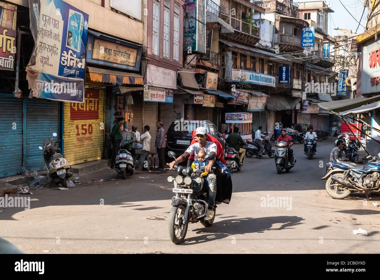 Bhopal, Madhya Pradesh,India - March 2019: An Indian man rides a motorcycle with his family in a busy market street in the old city area of Bhopal. Stock Photo