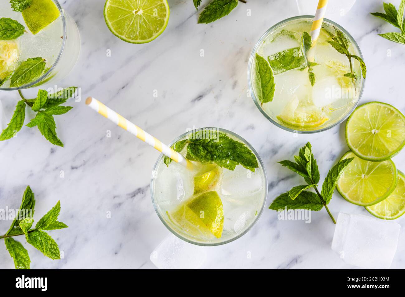 Mojito cocktail or mocktail, traditional fresh drink with lime and mint. With paper straws in the drinks. Top view, from above. On a white marble tabl Stock Photo