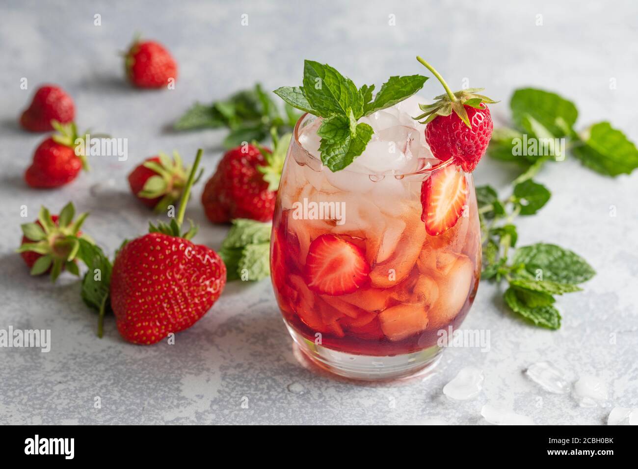 Strawberry drink mojito. Mocktail or cocktail with strawberries and mint leafs. The refreshing red drink is on a gray background with copy space on to Stock Photo