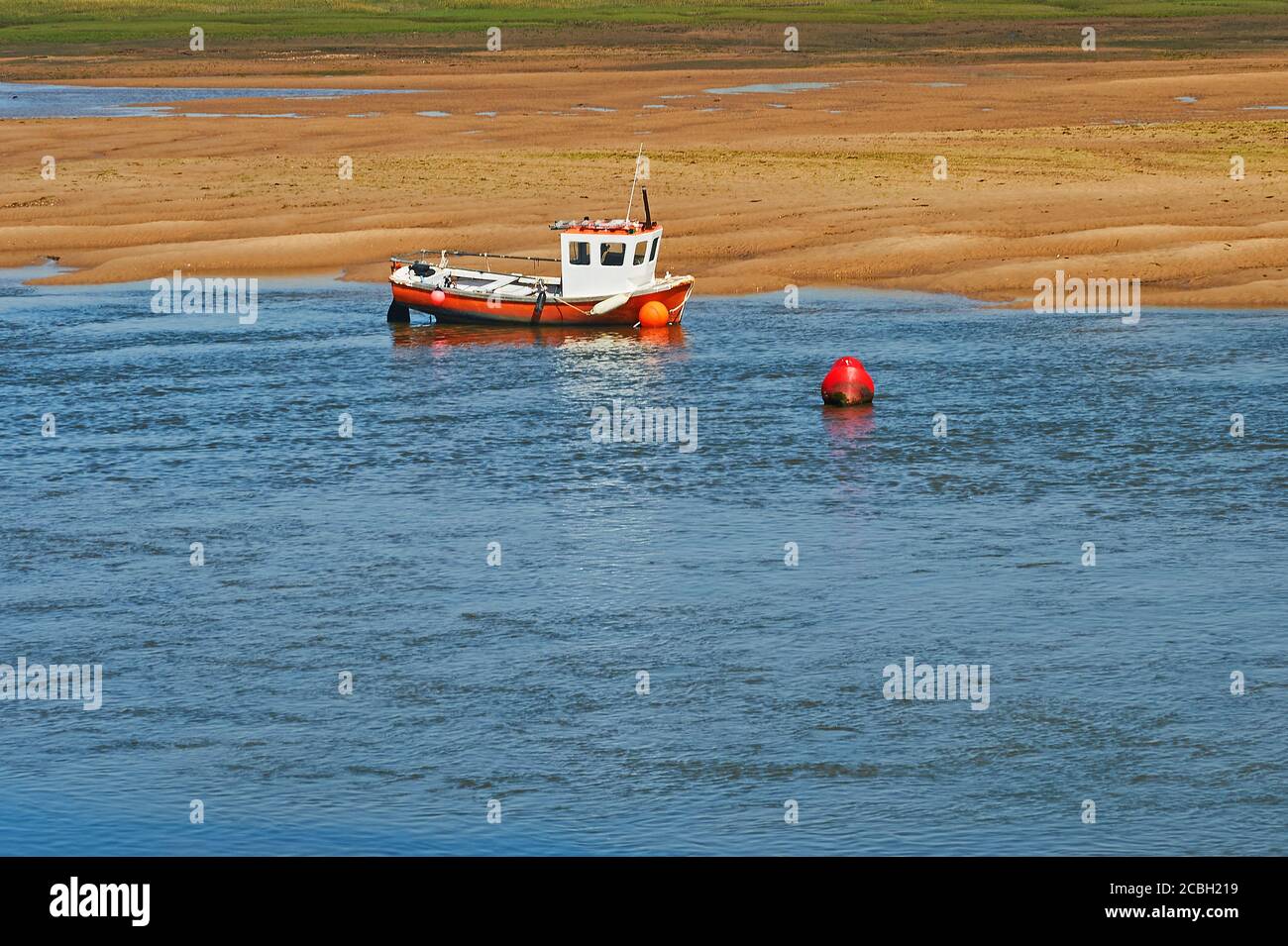 Boats along the sand banks created by low tide at Wells next the Sea, Norfolk Stock Photo