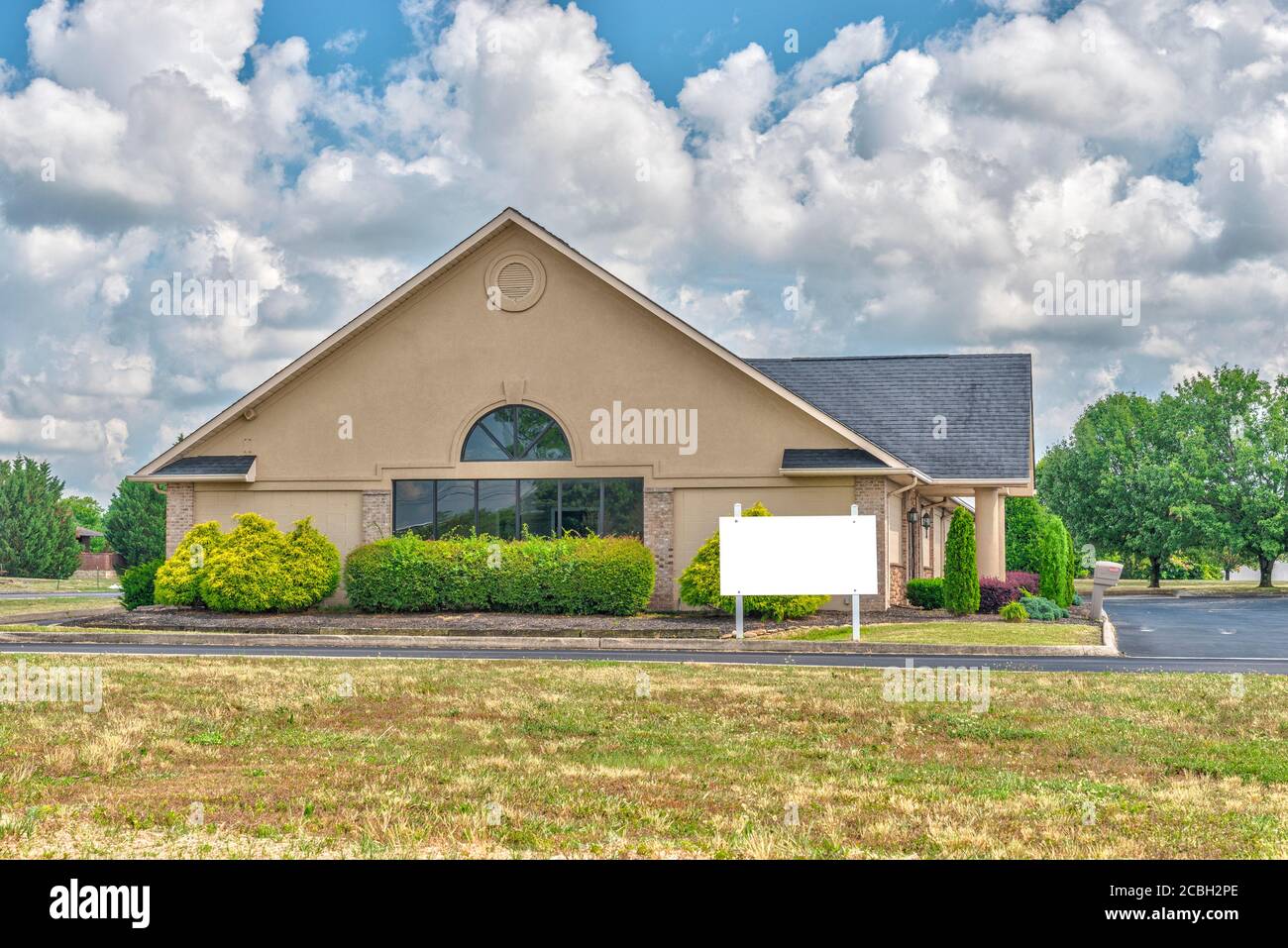 Horizontal shot of a bankrupt commercial building complex with a blank white sign next to it. Stock Photo