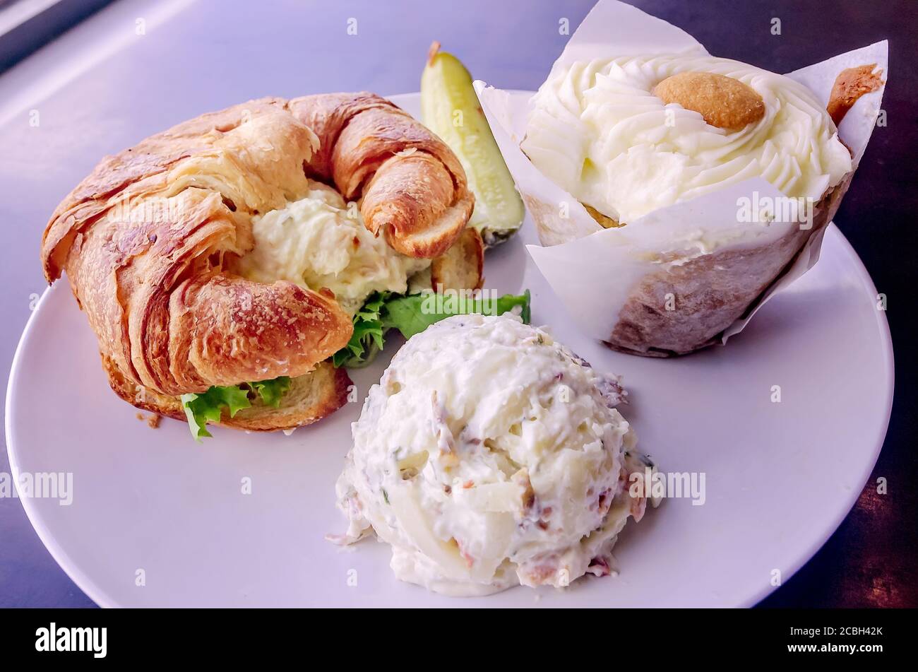 A lunch plate with a chicken salad croissant, potato salad, and a banana pudding cupcake is served at Crave Bistro/Cupcakery in Cleveland, Mississippi. Stock Photo