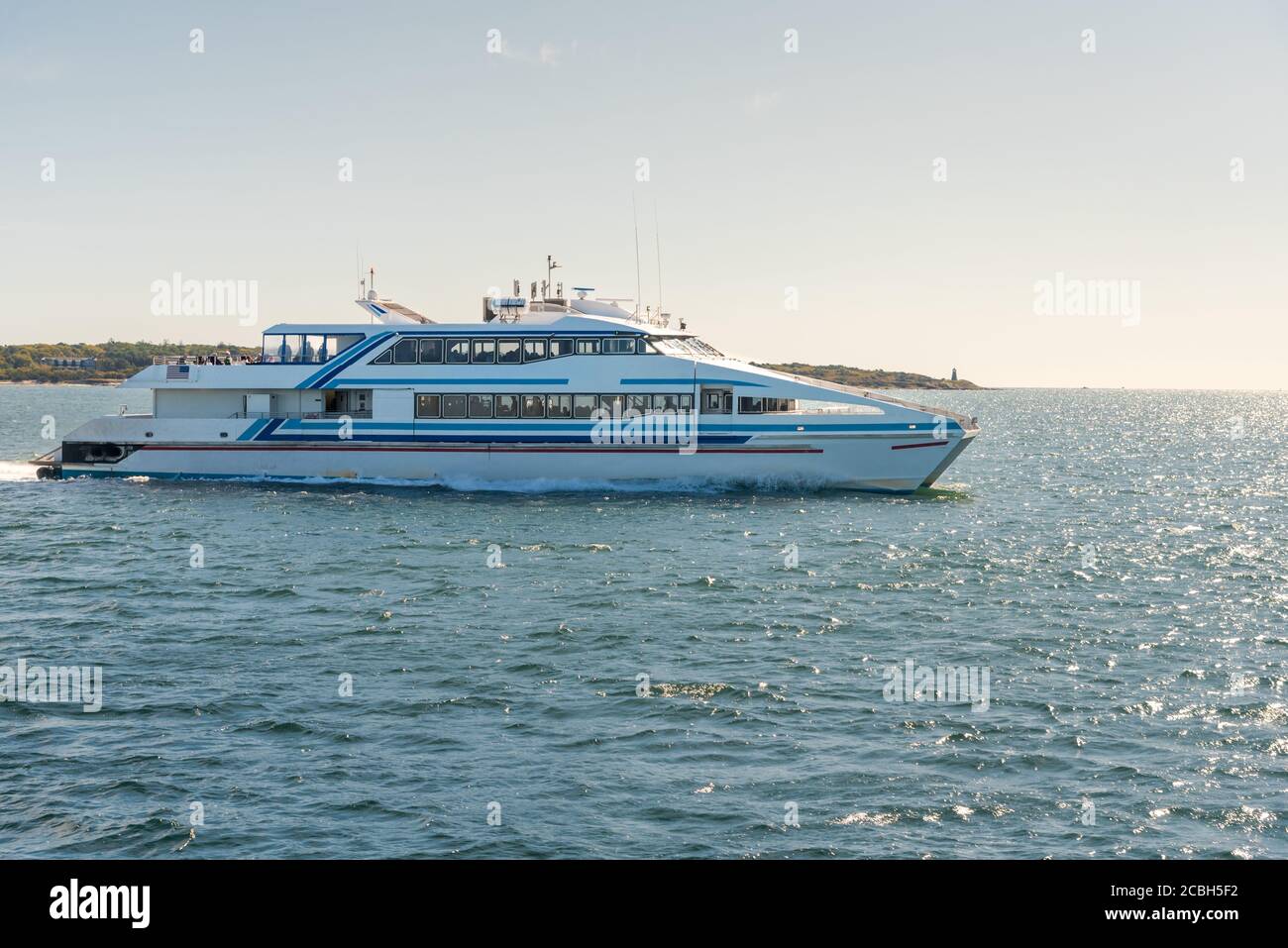 High-speed passenger ferry leaving a harbour on a sunny autum day Stock Photo